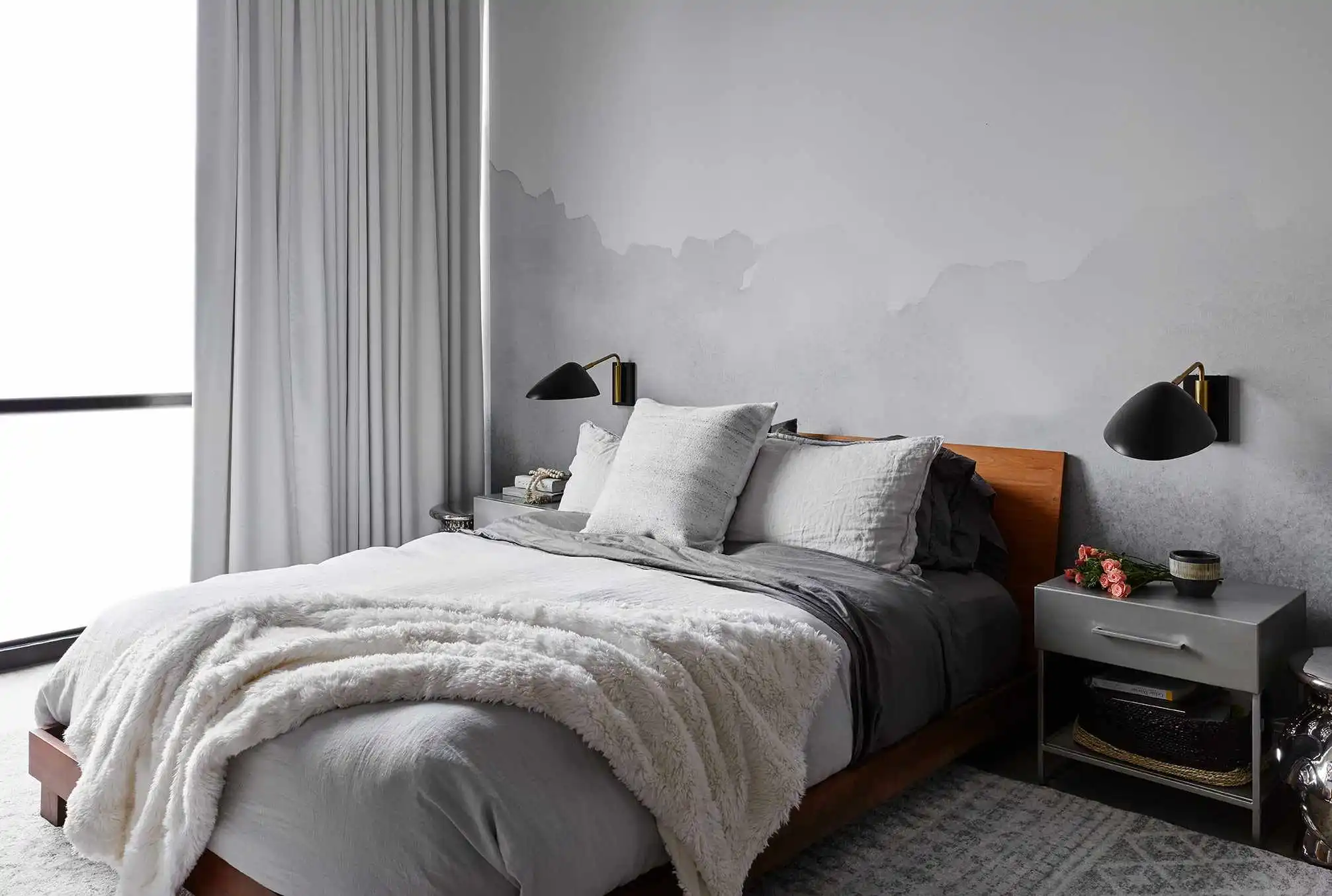 Industrial small bedroom featuring grey concrete wall and black wall sconces.