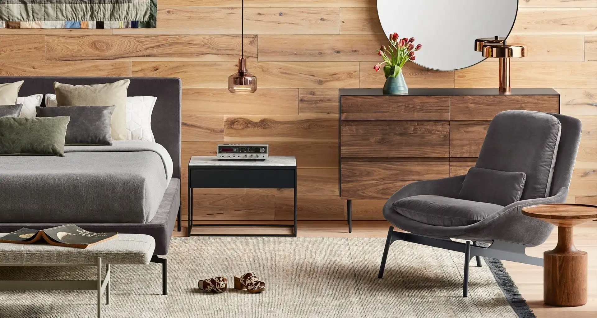 Men's small bedroom with black geometric wallpaper and tan headboard.