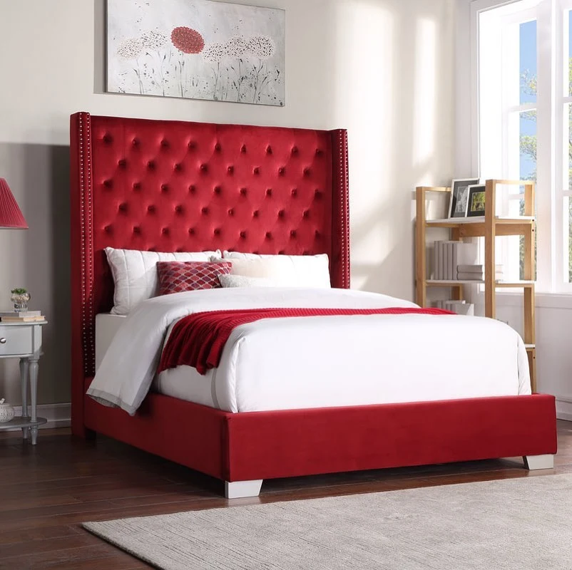 Red velvet tufted bed with neutral walls.