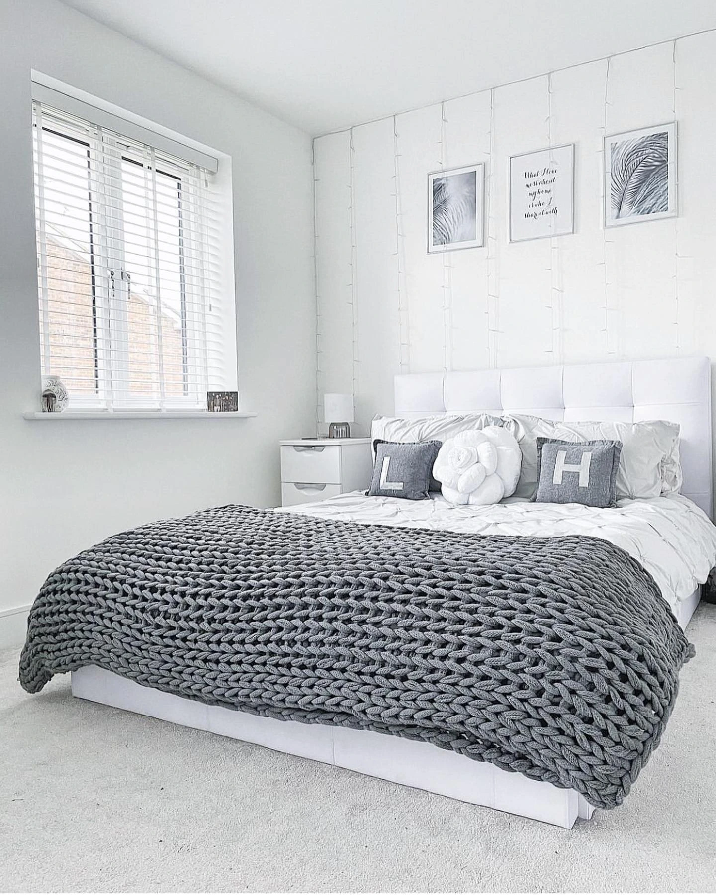 Minimalist white bedroom with a chunky gray knit blanket.