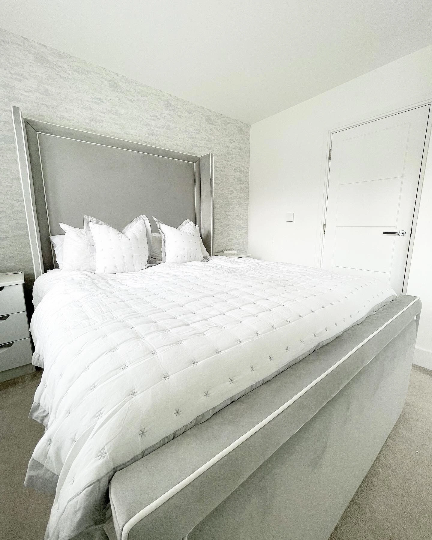 Luxurious bedroom with a large tufted gray headboard.