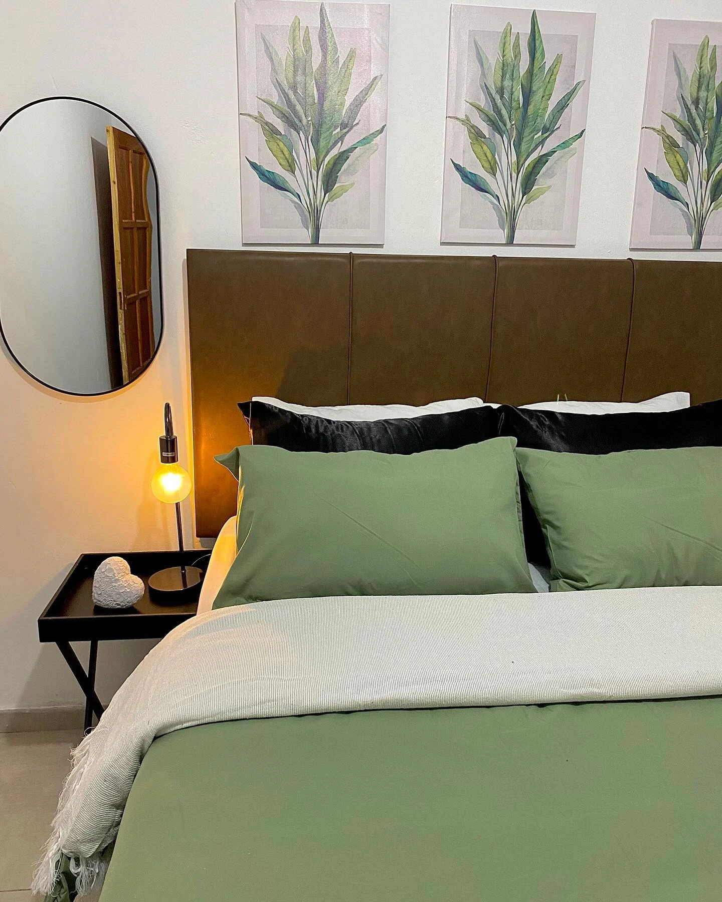 Earthy small bedroom with olive bedding and botanical art.