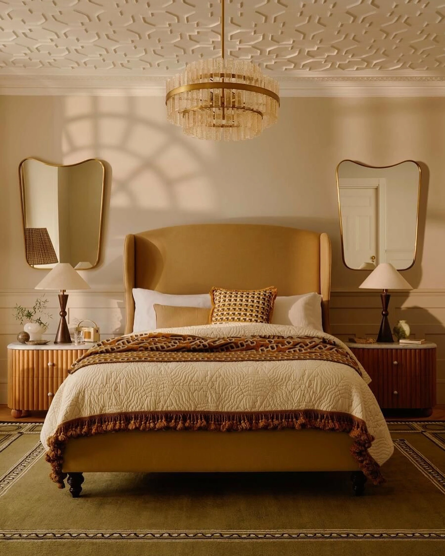Vintage glamorous bedroom with mustard bed and chandelier.