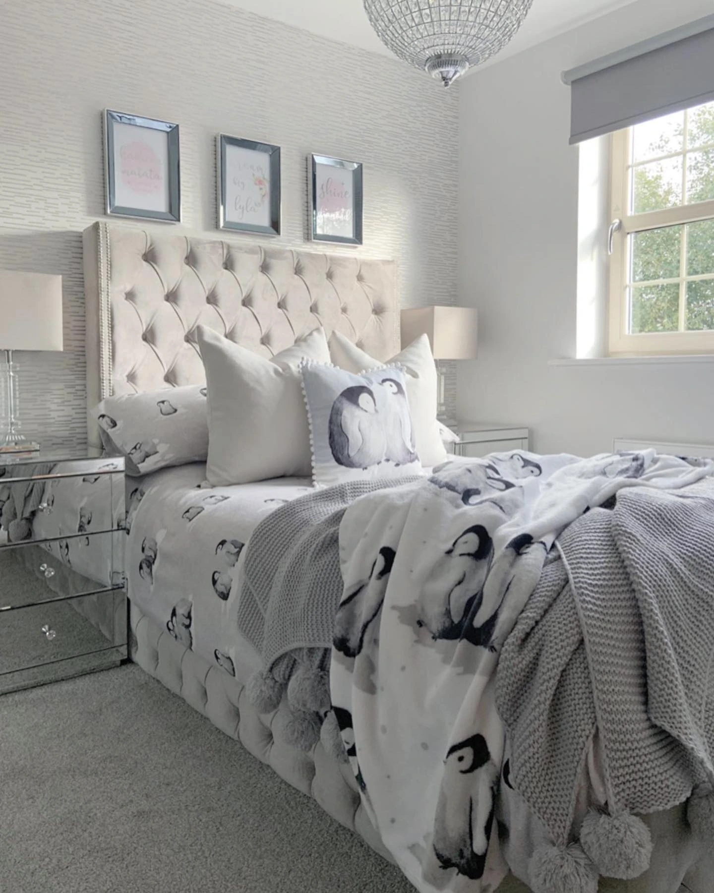 Bed with a velvet headboard and penguin bedding.  