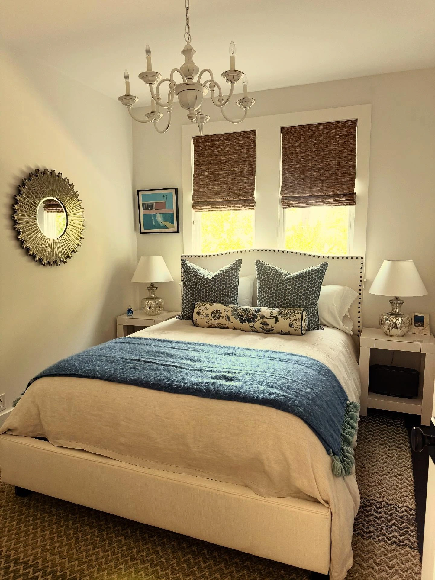 Bedroom with a gold sunburst mirror.  