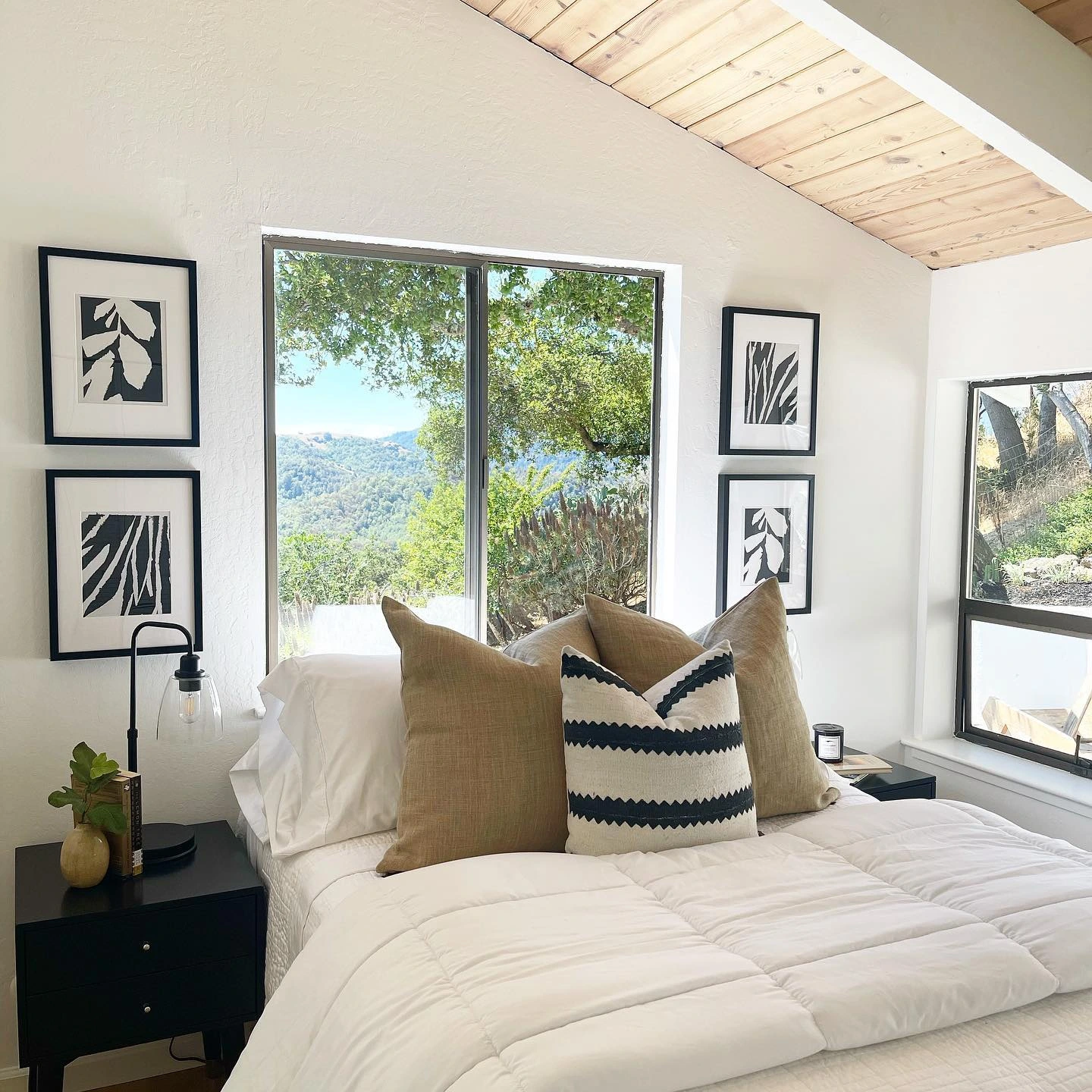 Bed with neutral pillows and black-and-white art.  