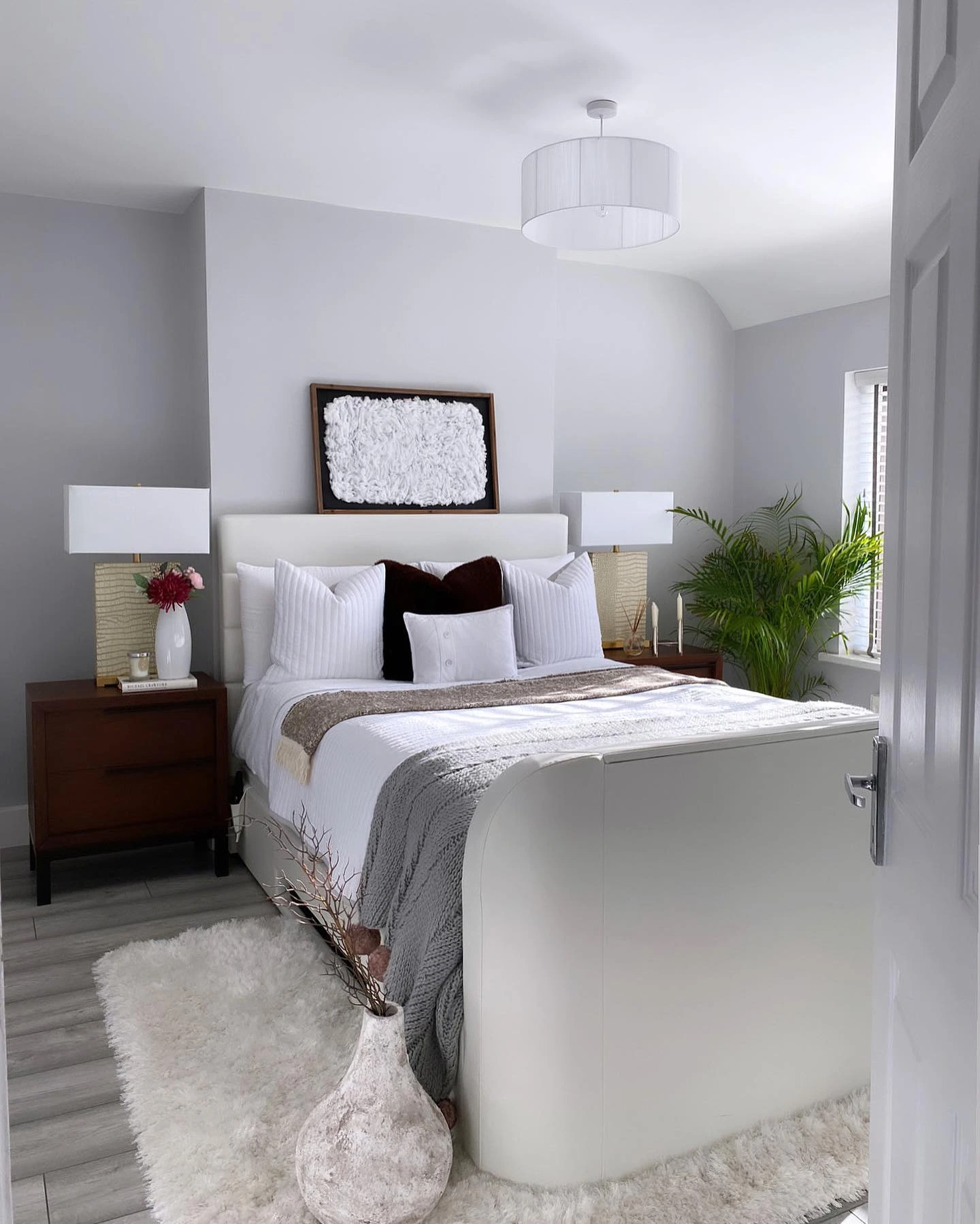 Blue accent wall bedroom with large white dresser and modern art.